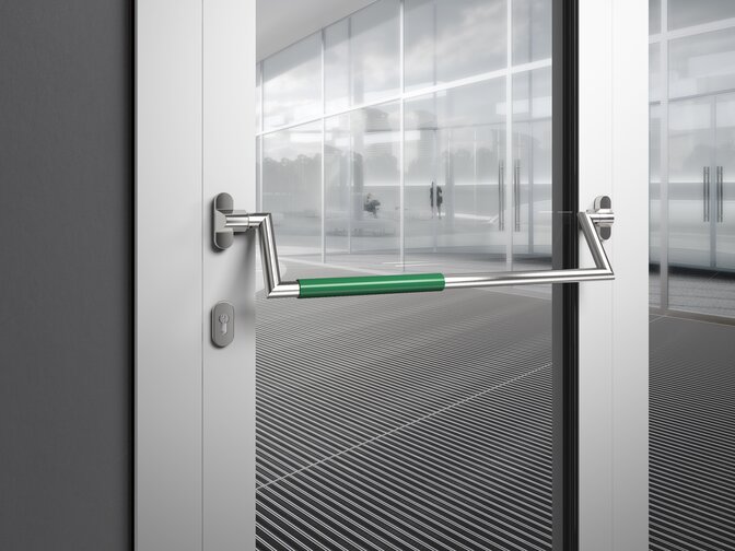 HEWI panic bar stainless steel matt Panic bar on a public building door made of matt polished stainless steel with green polyamide handle tube