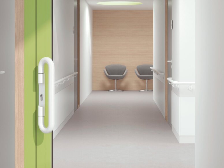 A glass door with a green frame and a white door handle in a white corridor