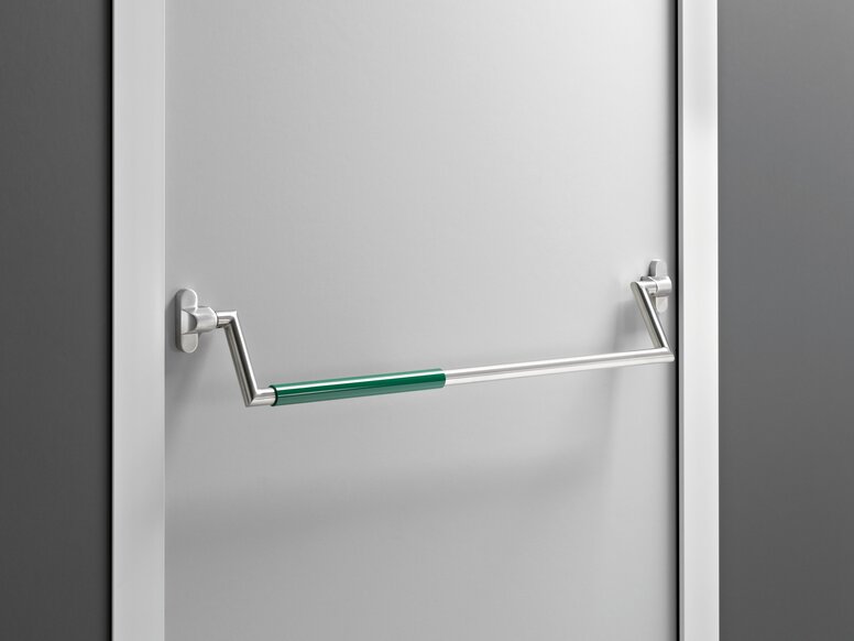 HEWI panic bar Stainless steel panic bar with a green grip section and two brackets on a white door with a frame