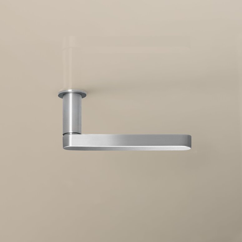 Nickel-effect door handle with a rectangular handle and a round rose on a beige-coloured wall