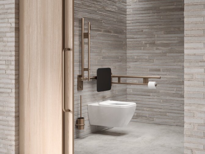 WC mit seitlichem klappbarem Stützgriff in einem barrierefreien öffentlichen WC mit Waschtischbereich und mehreren Waschbecken