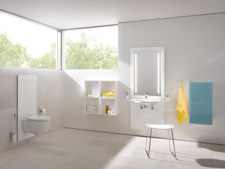 HEWI S 50 WC-Modul Weißes WC-Modul in einem hellen Badezimmer mit beleuchtetem Spiegel über dem Waschbecken, davor ein Hocker mit weißer Sitzfläche