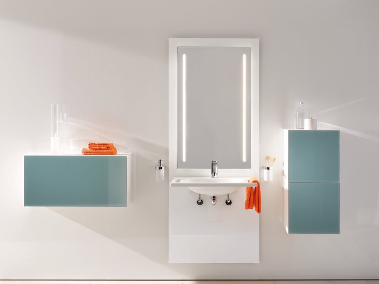 White washbasin module with a rectangular mirror and two taps against a light-coloured wall, flanked by a light blue wall cabinet on the left and a tall light blue cabinet on the right
