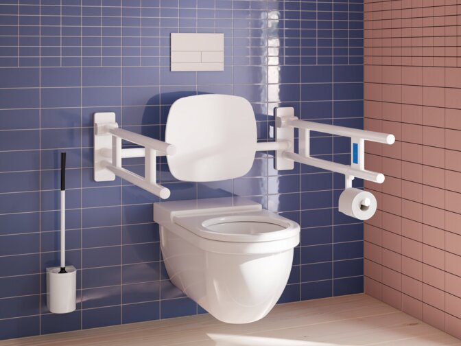 Wandhängendes WC mit Rückenlehne, zwei weißen Stützklappgriffen, WC-Papierhalter und Toilettenbürste vor Fliesen in Blau und Rosa