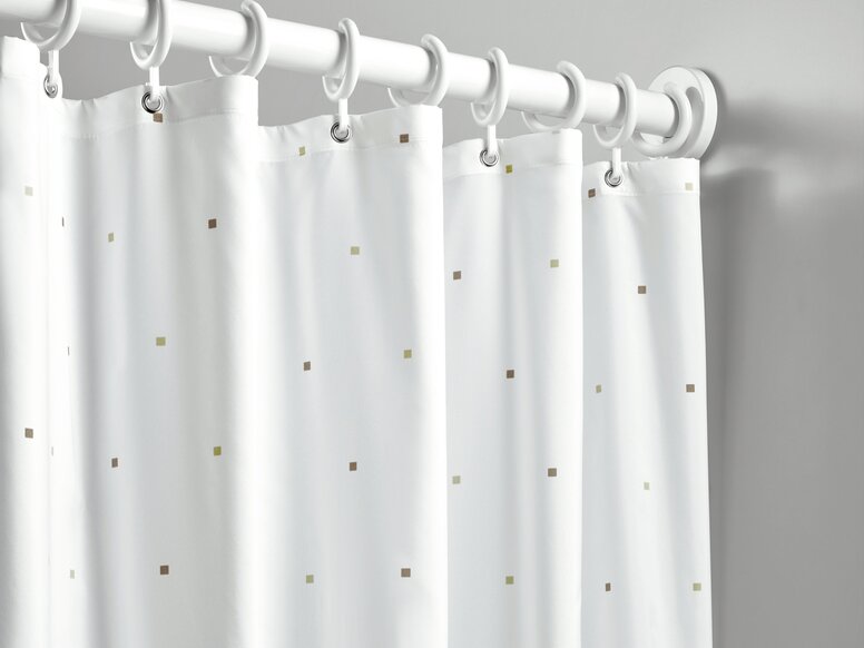 A shower curtain featuring small squares as a design detail, with white rings, hung on a white curtain rail against a light grey wall