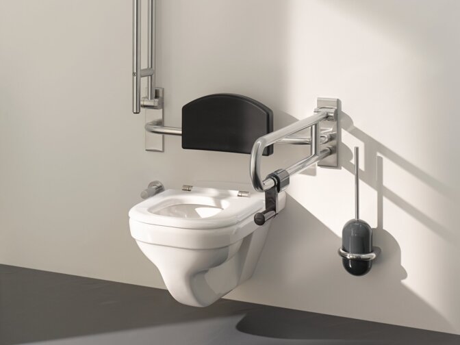 WC mit klappbarer Rückenlehne und zwei links und rechts montierten klappbaren Stützgriffen im barrierefreien WC-Bereich an weißer Wand