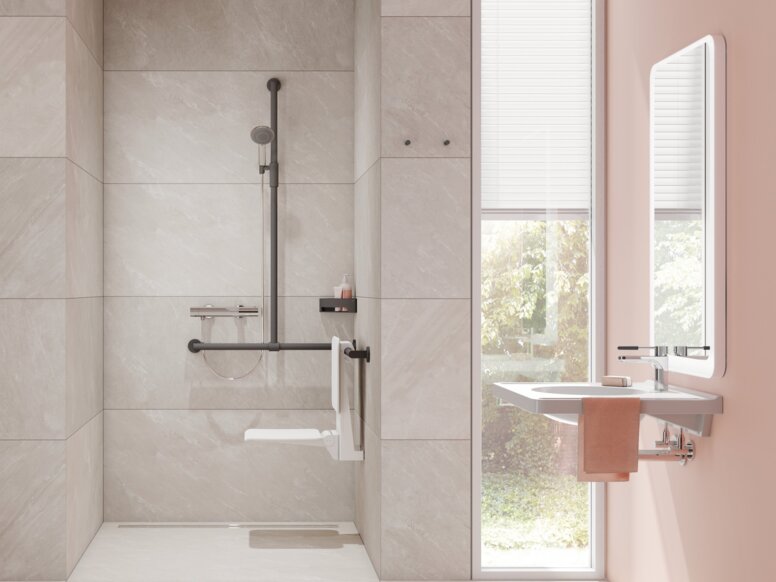 Klappsitz mit Rückenlehne und Brausehalterstange im barrierefreien Badezimmer mit unterfahrbarem Waschtisch vor einer Fensterfront