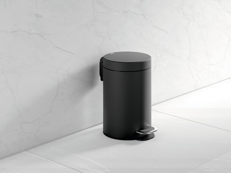 HEWI System 900 wastebin Black powder-coated bin with a foot pedal and a round cover, set against a white marble wall