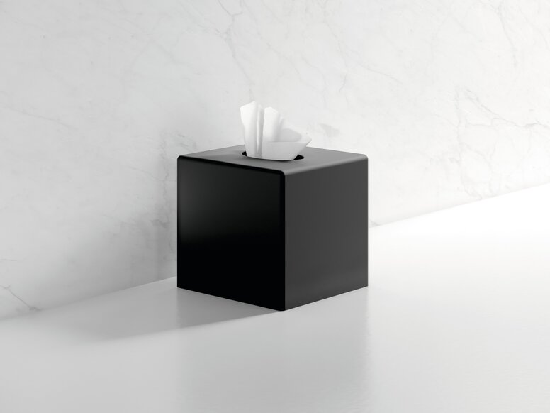 HEWI System 900 paper tissue dispenser Black powder-coated cube-shaped tissue dispenser with an open cover and paper tissues, set against a white marble wall