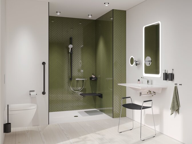 A support rail next to a WC, a black hinged seat and a black shower handrail in the shower with a green tiled wall