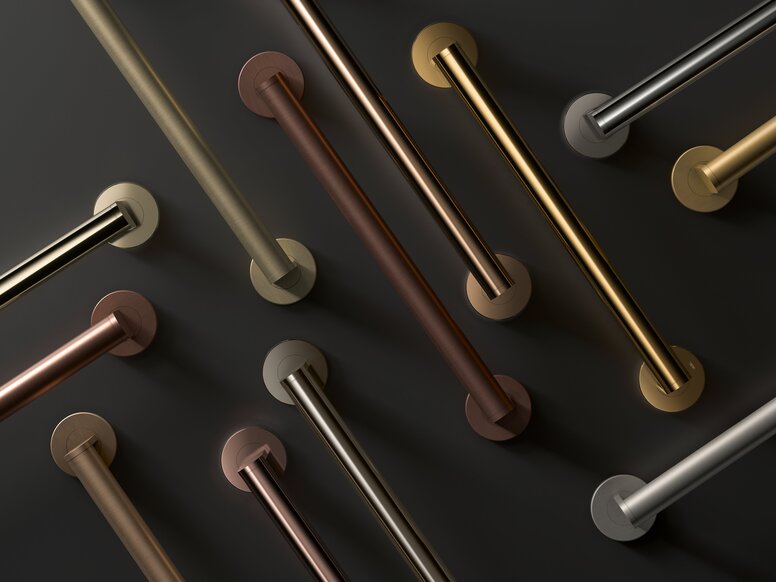 HEWI System 900 Grab Rails Several diagonally arranged grab rails in different shades of gold, bronze and silver-grey against a dark grey background