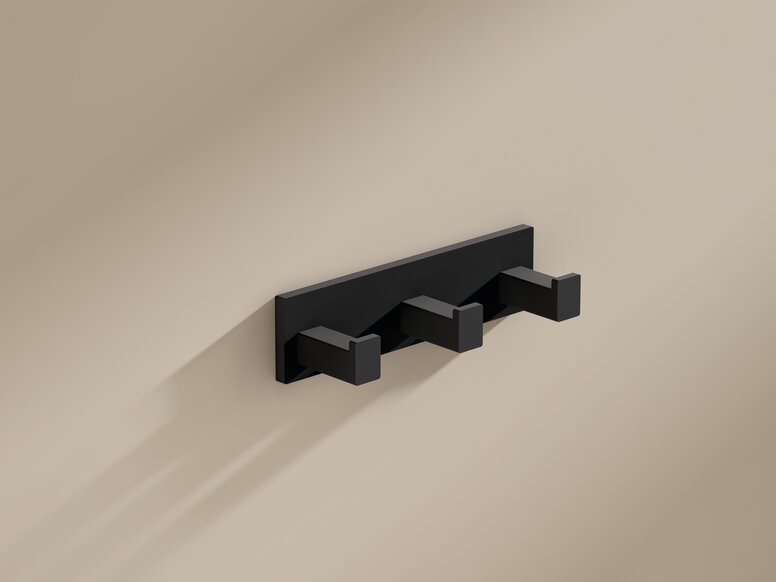 Black powder-coated coat rack with three square hooks on a beige wall