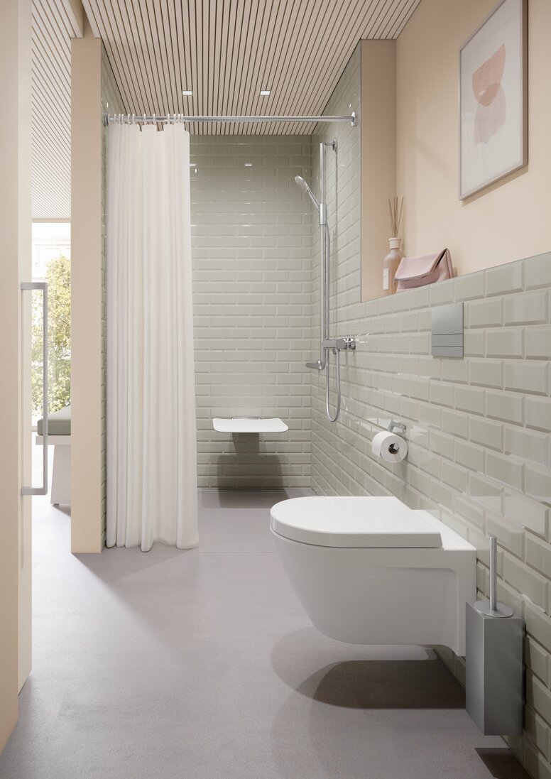 A hinged seat in a shower area with a rail with shower head holder, in front of which is a WC area with a toilet brush and a toilet roll holder