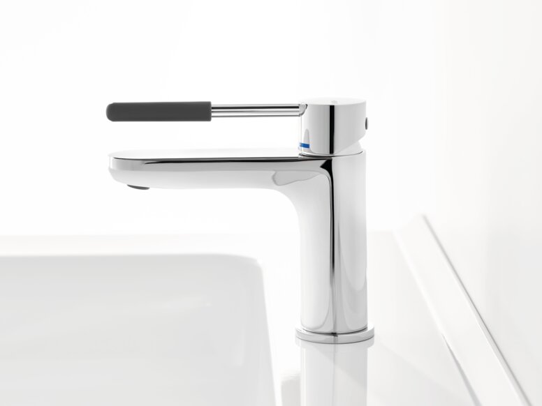 HEWI AQ single-lever washbasin mixer tap Chrome-plated tap with a long lever handle and dark grey grip sleeve on a white washbasin against a white background