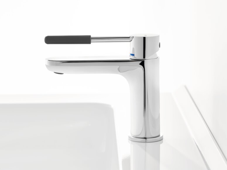 HEWI AQ single-lever washbasin mixer tap Chrome-plated tap with a long lever handle and dark grey grip sleeve on a white washbasin against a white background
