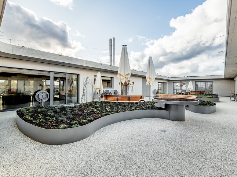 Innenhof im Haslibrunnen in der Schweiz Pflanzbeete mit integrierten Holzliegen im Innenhof