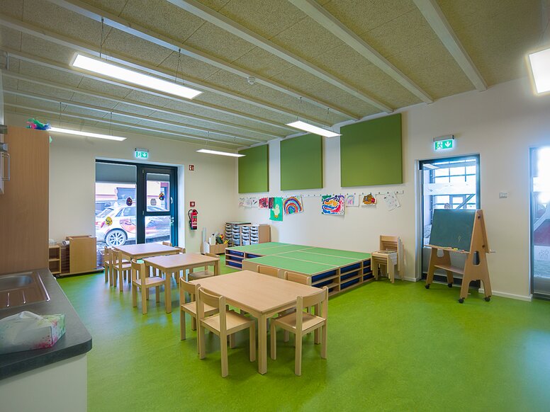Group room of the day care centre "In der Kammgarnspinnerei" Group room of a day care centre with green floor and wooden tables and chairs